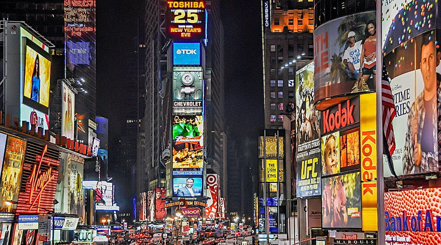 A lively city intersection at night, lit by hundrets of advertising displays