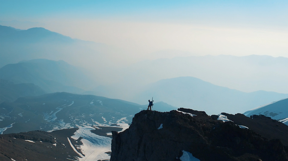 Hilltop with hiker and mountain range in the background